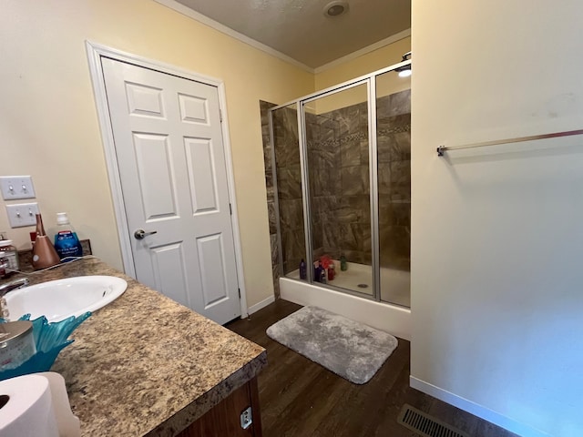 bathroom featuring vanity, wood-type flooring, crown molding, and walk in shower