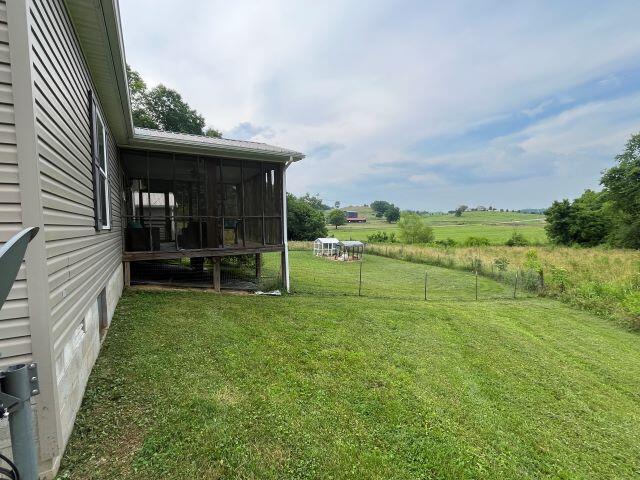 view of yard featuring a sunroom and a rural view