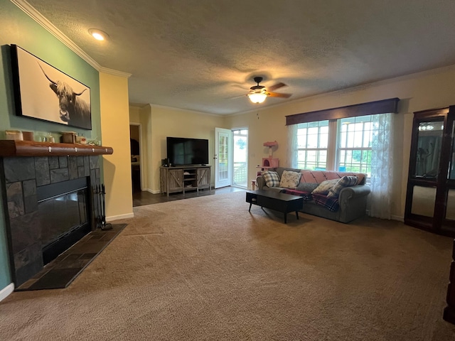 living room with ceiling fan, dark colored carpet, a stone fireplace, crown molding, and a textured ceiling