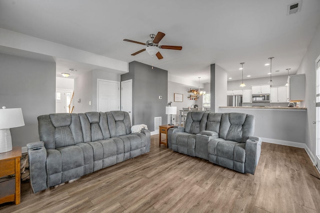 living room featuring light hardwood / wood-style flooring and ceiling fan with notable chandelier