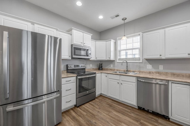 kitchen with wood-type flooring, white cabinetry, sink, and appliances with stainless steel finishes