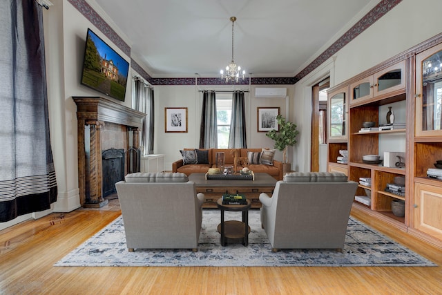 living room with a chandelier, wood-type flooring, a wall mounted AC, and ornamental molding