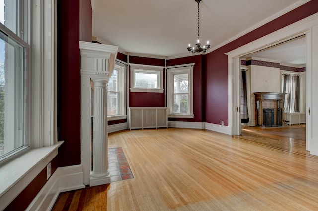 unfurnished dining area with hardwood / wood-style flooring, radiator heating unit, crown molding, and a chandelier