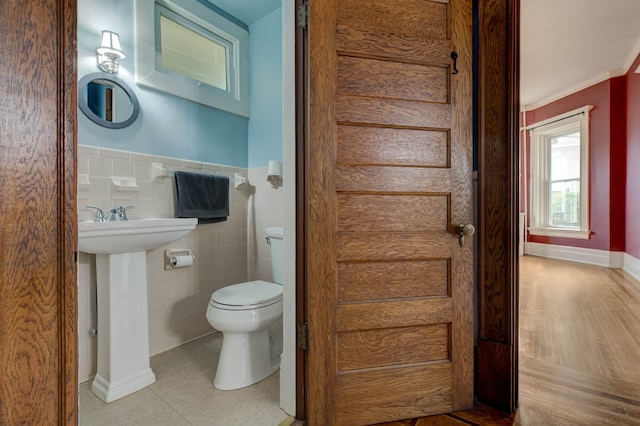 bathroom with crown molding, wood-type flooring, tile walls, and toilet