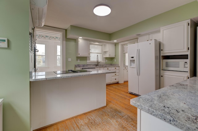 kitchen featuring light stone counters, white appliances, sink, light hardwood / wood-style flooring, and white cabinets