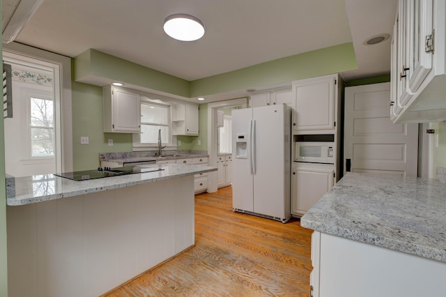 kitchen with white cabinetry, light stone counters, white appliances, and light wood-type flooring