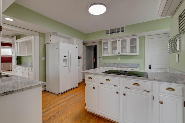 kitchen with white cabinets, black electric stovetop, light hardwood / wood-style flooring, and white fridge with ice dispenser