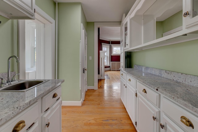 interior space with light wood-type flooring, white cabinetry, and sink