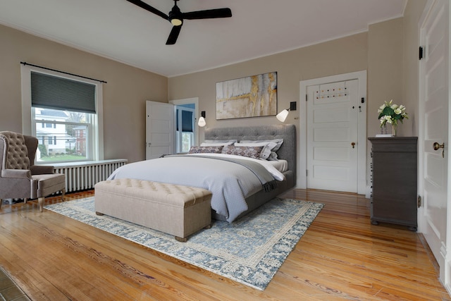 bedroom with radiator heating unit, ceiling fan, ornamental molding, and hardwood / wood-style floors