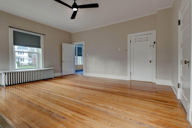 empty room featuring light hardwood / wood-style flooring, radiator, crown molding, and ceiling fan