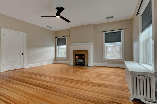 unfurnished living room featuring ceiling fan, a healthy amount of sunlight, light wood-type flooring, and radiator