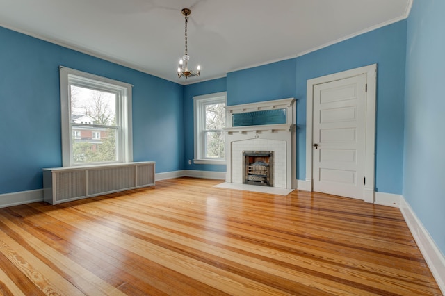 unfurnished living room with radiator heating unit, light hardwood / wood-style floors, plenty of natural light, and ornamental molding