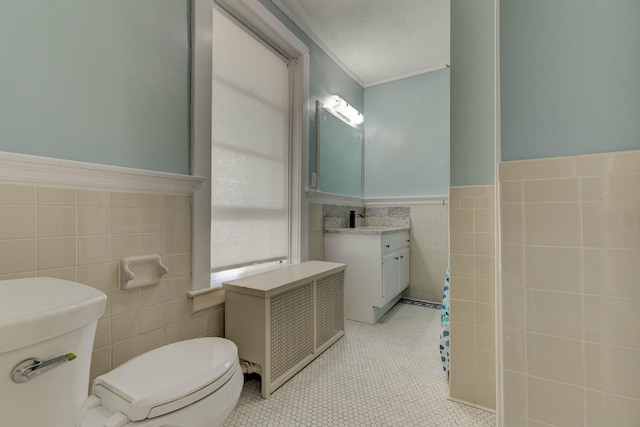 bathroom featuring vanity, radiator, crown molding, toilet, and tile walls