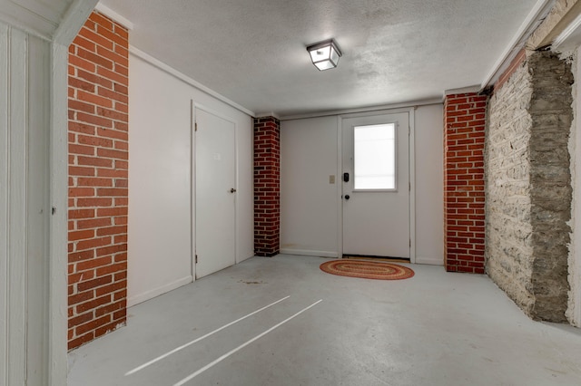 foyer entrance featuring a textured ceiling and brick wall