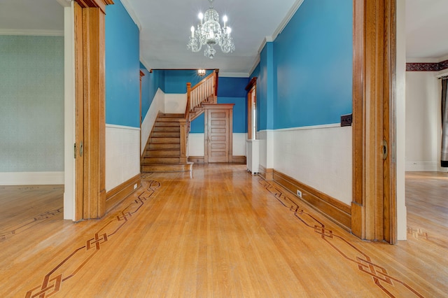 interior space with a chandelier, wood-type flooring, and ornamental molding