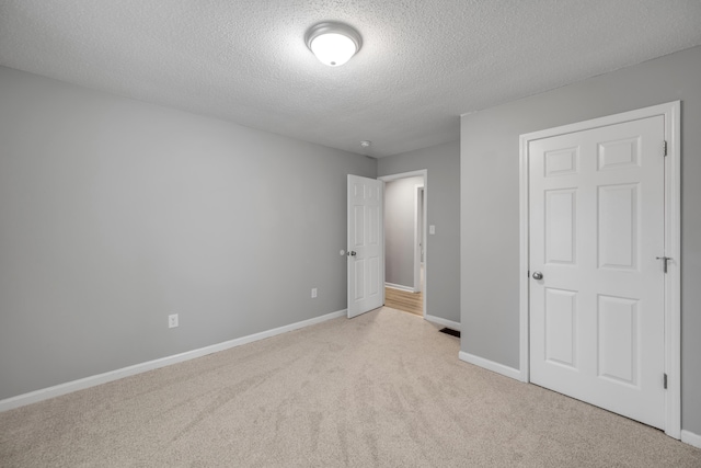 unfurnished bedroom featuring light colored carpet and a textured ceiling