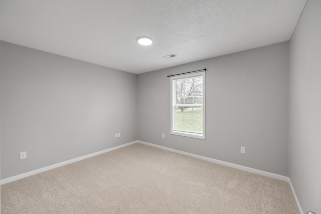 carpeted empty room featuring a textured ceiling