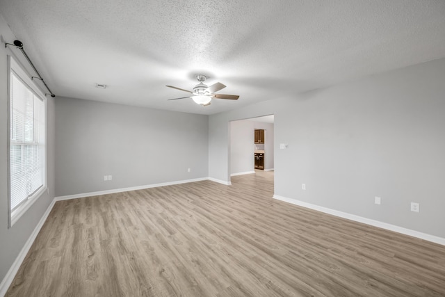 empty room with ceiling fan, light hardwood / wood-style flooring, and a textured ceiling