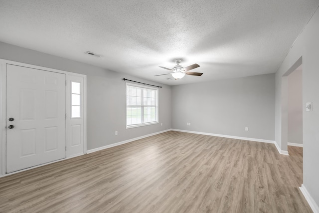 foyer entrance with ceiling fan, a textured ceiling, and light wood-type flooring