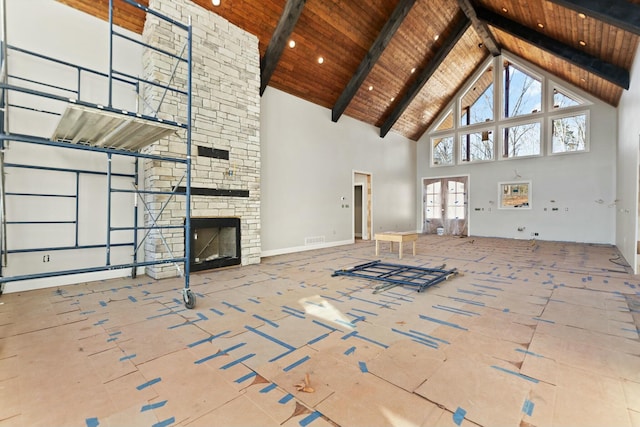 unfurnished living room featuring beam ceiling, french doors, wooden ceiling, a stone fireplace, and high vaulted ceiling