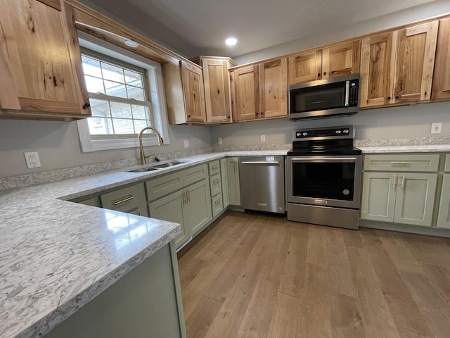 kitchen featuring sink, stainless steel appliances, light hardwood / wood-style floors, and light stone countertops