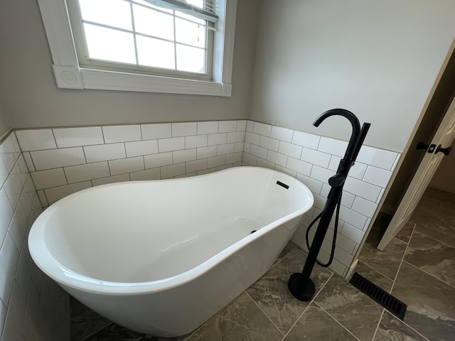 bathroom featuring a bathing tub and tile walls