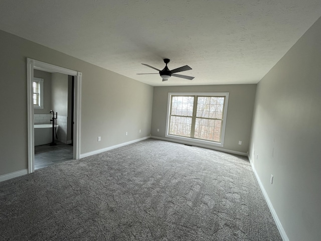 spare room with ceiling fan, plenty of natural light, a textured ceiling, and dark carpet