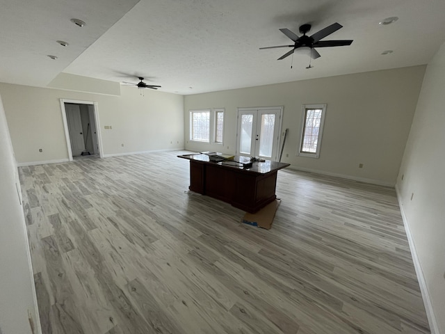 unfurnished living room with ceiling fan, light hardwood / wood-style floors, and french doors