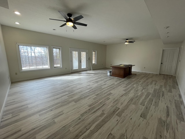 unfurnished living room with light hardwood / wood-style flooring, a wealth of natural light, ceiling fan, and french doors