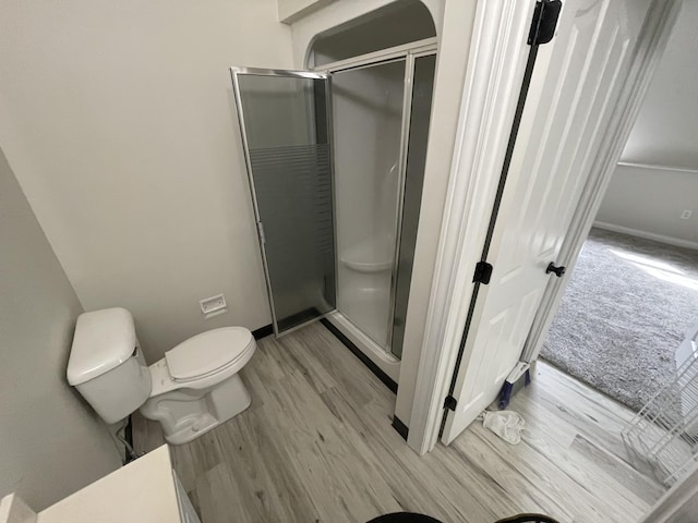 bathroom with walk in shower, toilet, and hardwood / wood-style flooring