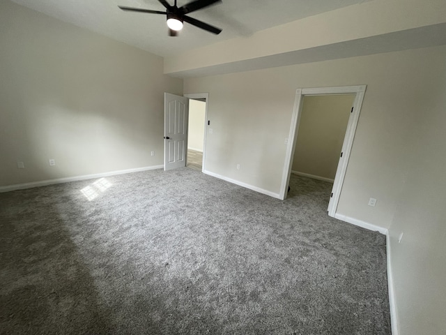 empty room with ceiling fan and dark colored carpet