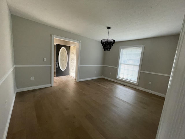 spare room with hardwood / wood-style flooring, a chandelier, and a textured ceiling