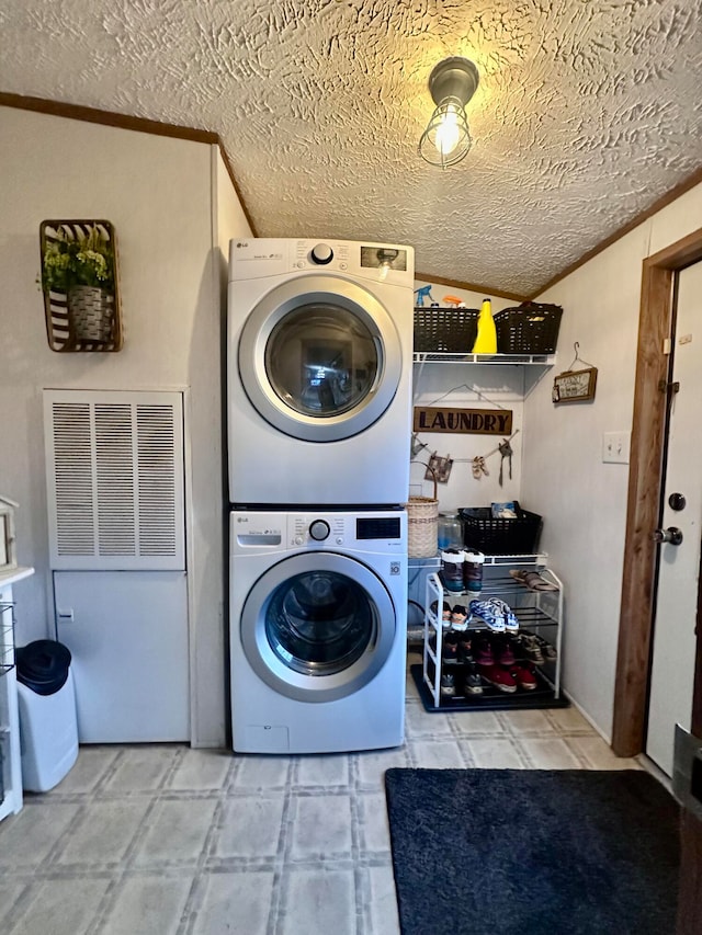 washroom with a textured ceiling, stacked washer and dryer, and crown molding