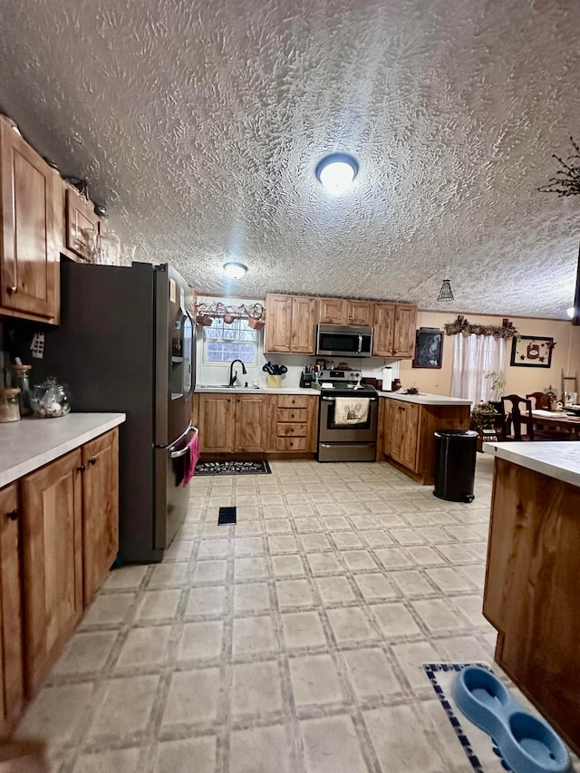 kitchen with kitchen peninsula, a textured ceiling, stainless steel appliances, and sink