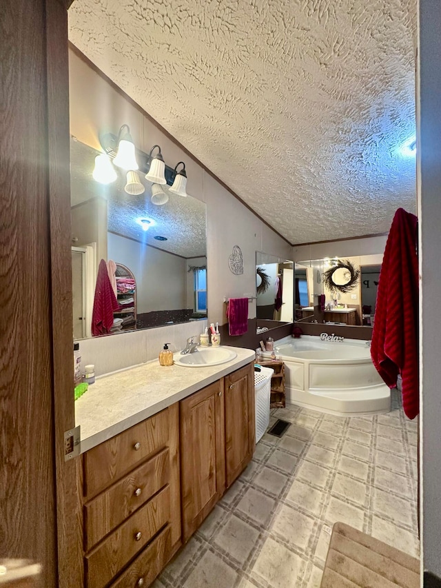 bathroom featuring a tub to relax in, vanity, and a textured ceiling