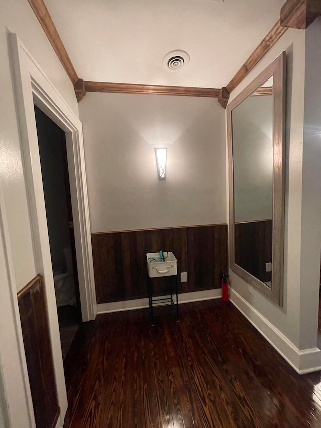 unfurnished room featuring ornamental molding, dark wood-type flooring, and wooden walls