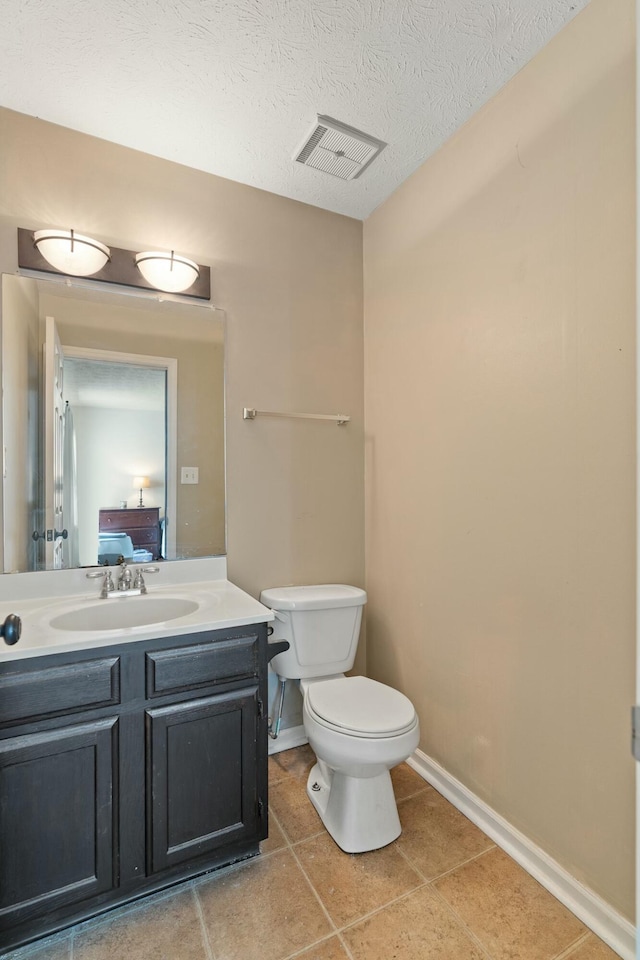 bathroom featuring tile patterned flooring, vanity, toilet, and a textured ceiling