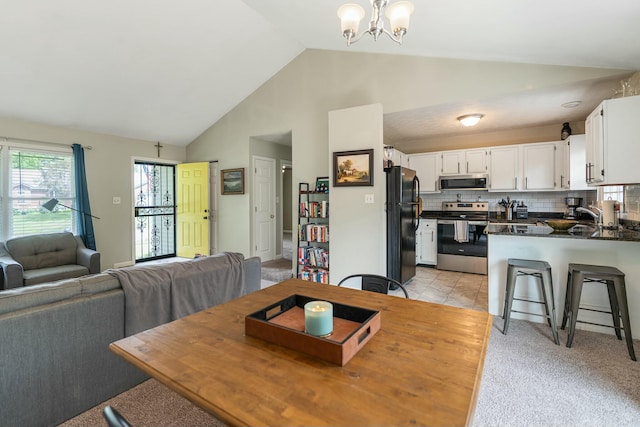 carpeted dining room featuring a notable chandelier, sink, and high vaulted ceiling