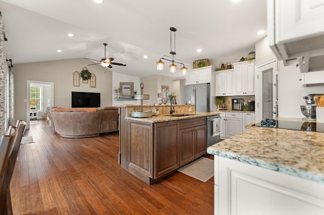 kitchen with white cabinetry, sink, stainless steel appliances, an island with sink, and vaulted ceiling