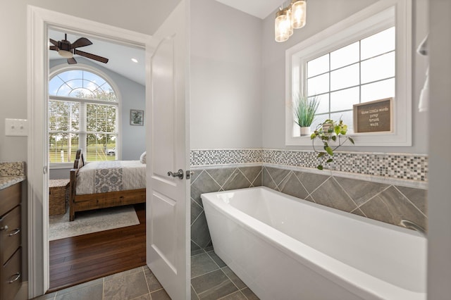 bathroom with vanity, a bathtub, vaulted ceiling, hardwood / wood-style flooring, and ceiling fan