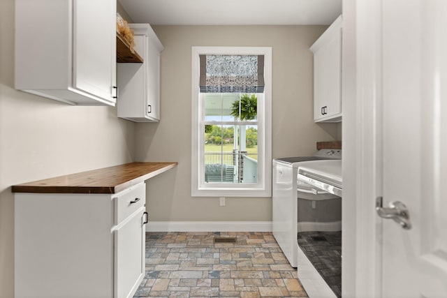 clothes washing area with cabinets and washing machine and clothes dryer