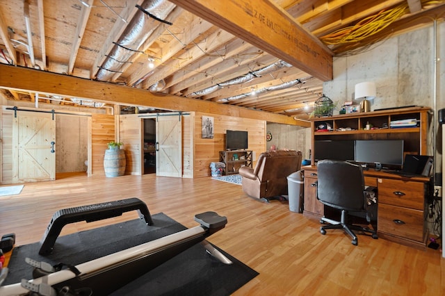 workout area with a barn door and wood-type flooring