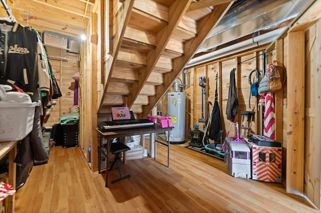 basement featuring water heater and hardwood / wood-style flooring