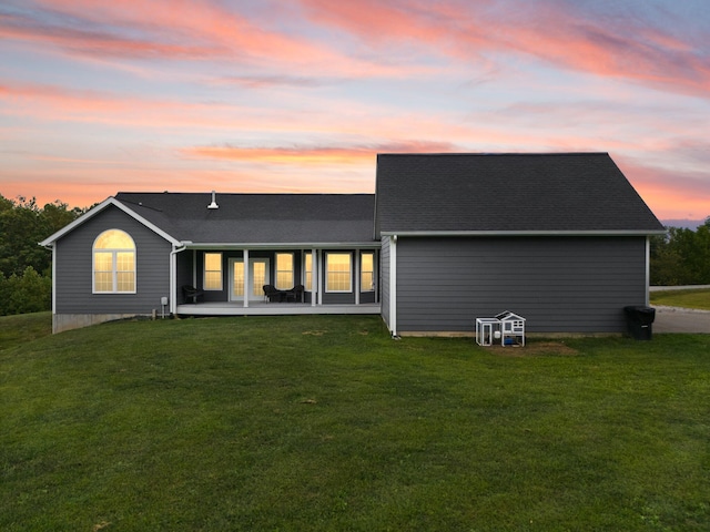 back house at dusk with a lawn