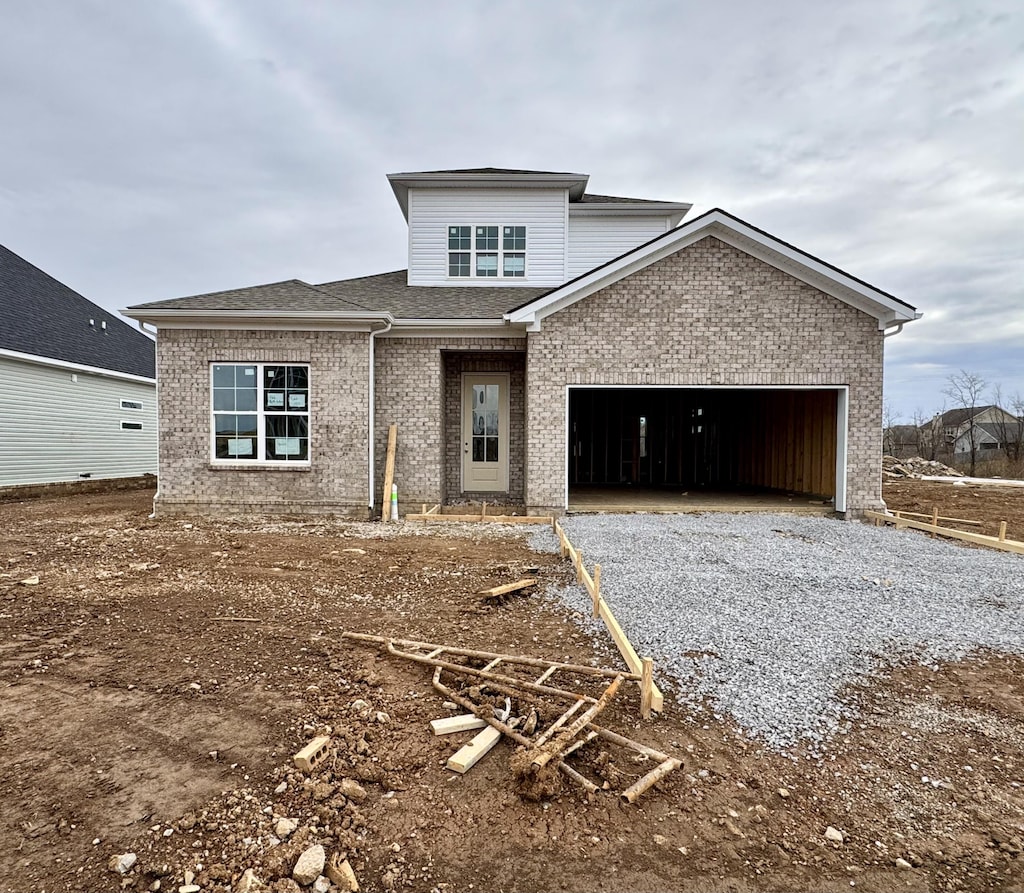 view of front facade featuring brick siding, an attached garage, a shingled roof, and driveway