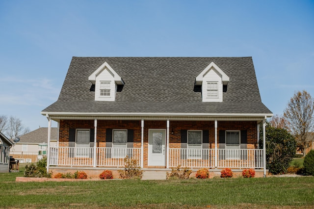 cape cod house featuring a porch and a front lawn