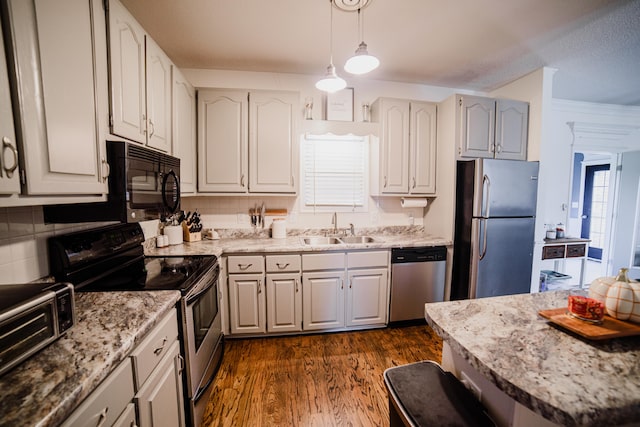 kitchen featuring white cabinets, sink, hanging light fixtures, dark hardwood / wood-style floors, and stainless steel appliances