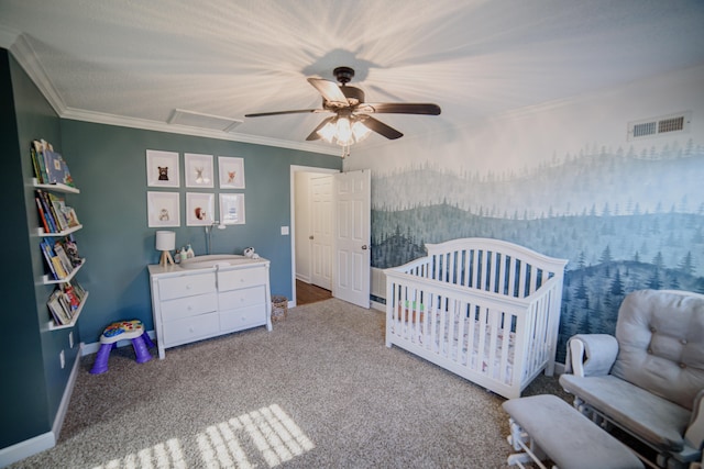 carpeted bedroom featuring ceiling fan, crown molding, and a nursery area