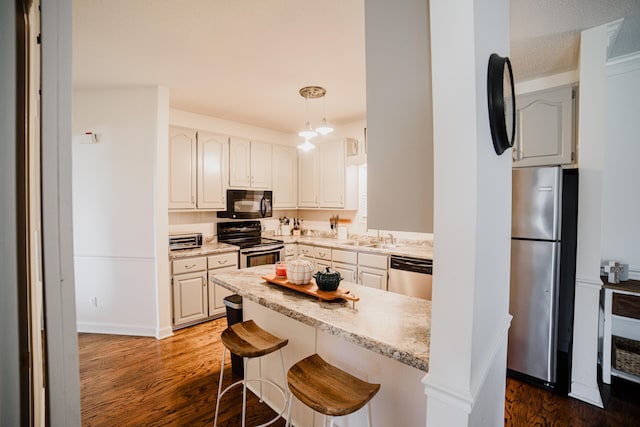 kitchen featuring white cabinetry, dark hardwood / wood-style flooring, kitchen peninsula, a kitchen bar, and black appliances