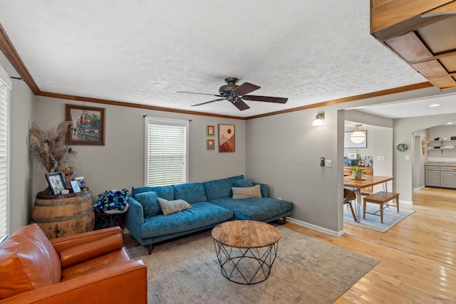 living room with ornamental molding, ceiling fan, a textured ceiling, and light hardwood / wood-style floors